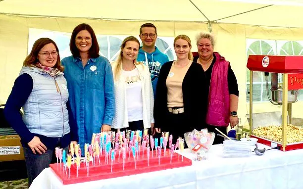 Sechs Helferinnen und Helfer des Fördervereins hinter dem Süßigkeitenstand mit Zuckerstangen, Marshmallows und einer Popcornmaschine.